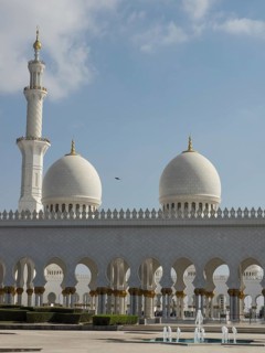 White mosque complex with elegant domes and a minaret under a clear sky, beautiful mosque with