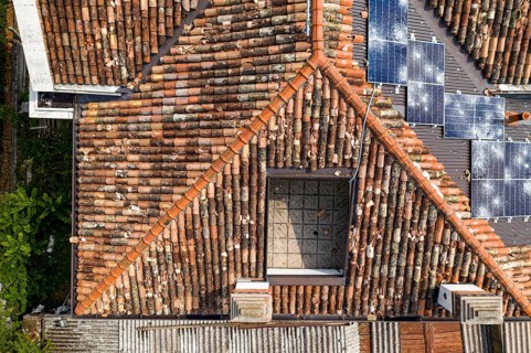A mix of old tiled roofs and new solar panels damaged seen from an aerial viewpoint
