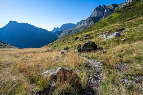 Mountaineer on hiking trail, mountain landscape with green mountain meadows and rocky peaks, Carnic
