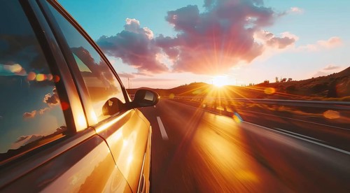 Low angle view of a modern luxury car on a road trip with a sunset in the background, AI generated