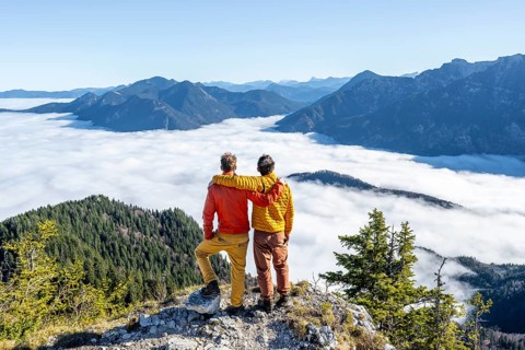 Two friends put their arms around each other's shoulders, mountaineers on the rocky summit of the