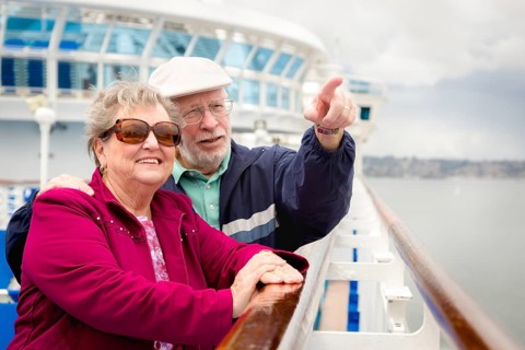 Senior adult couple enjoying the view from their passenger cruise ship railing