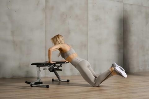 Unrecognizable athletic woman doing push ups with crossed legs on the floor in a gym