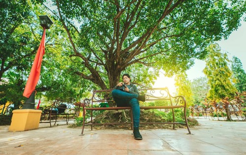 Photographer sitting on a bench checking his camera. Male photographer checking dslr camera sitting
