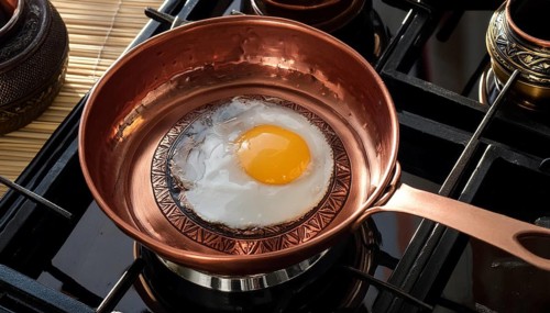 Metal, copper, a fried egg is fried in a copper pan