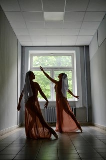 Silhouette of two ballerinas repeat dance steps in the corridor