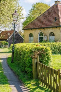 Traditional house in the village with surrounding meadow and hedges, illuminated by a lantern,
