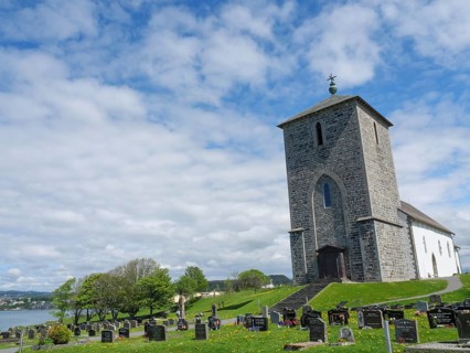 Church with cemetery under a cloudy sky on a green meadow, old stone church and many gravestones by