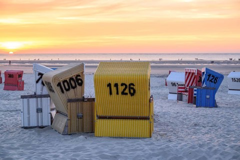 Beach chairs at sunset on the beach, focus on yellow basket, many colourful beach chairs on a warm