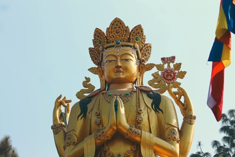 Ornate golden Avalokitesvara female Buddha statue against a clear blue sky background in Swayambhu