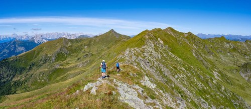 Mountaineer on a grassy ridge, idyllic mountain landscape with green mountain meadows, Carnic High