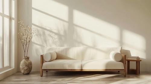A white couch sits in front of a white wall. Potted feather grass sit on the floor next to the