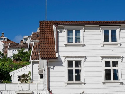 White wooden houses with red tiled roofs against a clear blue sky, white wooden houses with green