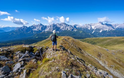 Mountaineers on a hiking trail between green mountain meadows on a mountain ridge, mountain