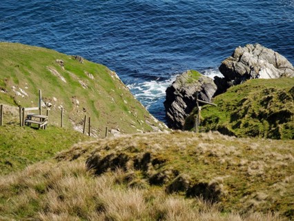 Cliffs and grassy hills on the coast overlooking the ocean, green meadows on a deep blue sea and a