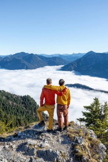 Two friends put their arms around each other's shoulders, mountaineers on the rocky summit of the