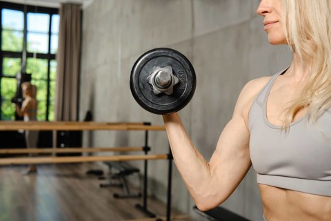 Closeup view of muscular female hand with dumbbell in the gym
