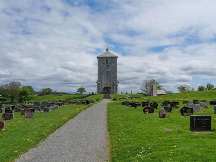 Stone church on a hill surrounded by a spacious cemetery with gravestones under a cloudy sky, old
