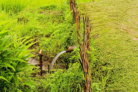 Water flowing from irrigation pipe spinning a small water wheel in canal in Chiang Khan, Thailand,