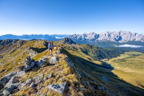 Mountaineer on a grassy ridge, mountain panorama, view of rocky mountain peaks of the Sesto