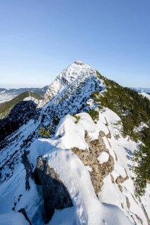 Mountain ridge of the Aiplspitz with summit cross, snow-covered mountain landscape with mountain