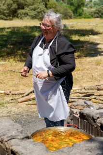 Cook with white apron collecting wood for the fire in the field to make a typical spanish paella