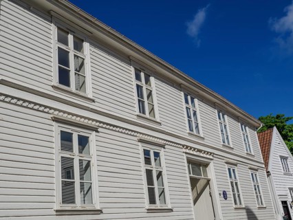 White wooden houses with many windows and red tiled roofs under a blue sky, white wooden houses