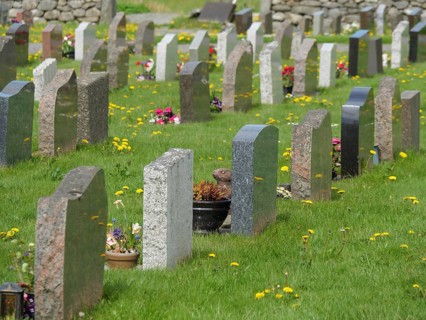 Row of gravestones on a green lawn with spring flowers in a quiet environment, old stone church and