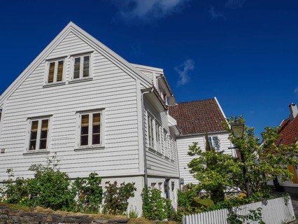 White houses with red tiled roof and green garden, sunny day with blue sky, white wooden houses