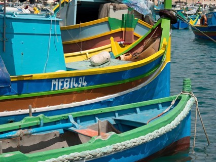 Colourful fishing boats in the harbour moored to the shore with ropes and floating in the water,