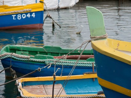 Colourful fishing boats moored in the clear water of the harbour with ropes, many colourful fishing