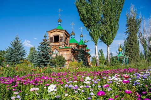 Colourful flowers in front of the Russian Orthodox Church Cathedral of the Holy Trinity, wooden