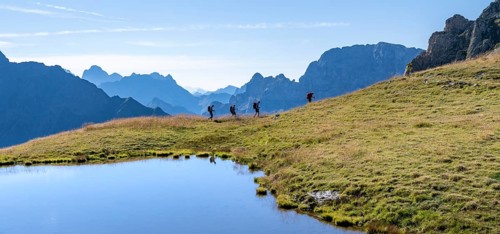 Group of mountaineers in front of mountain landscape, mountain lake and silhouettes of rocky