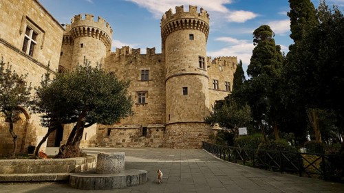 Super wide angle shot, Old castle with towers surrounded by trees under a clear blue sky,