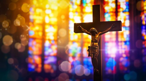 Crucifix with Jesus Christ on cross in church with light coming through stained glass windows,