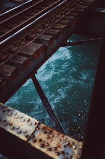 Close-up of the railway tracks with water in the background. Taken on a cloudy day in Tauranga, New