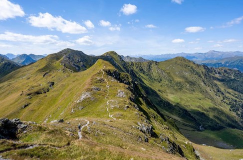 Hiking trail along a grassy mountain ridge, idyllic mountain landscape with green mountain meadows,