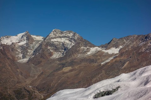 Snow covered mountains and rocky peaks under a clear blue sky, snow on high mountains in the alps,