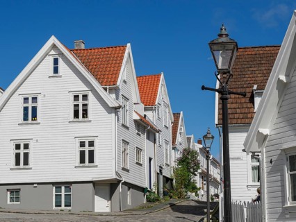 White wooden houses, streetlights and cobblestone street under blue sky, historic architecture with