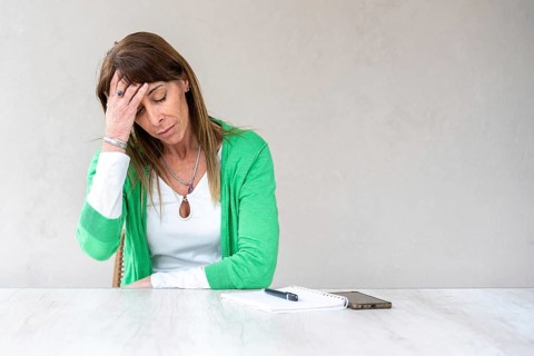 A mid-adult woman is holding one hand on her forehead