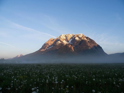Morning light falls on a mountain peak, Grimming, early morning fog on the meadow, near Irdning,