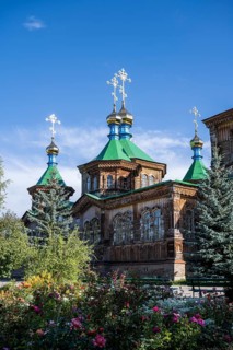 Flowers in front of the Russian Orthodox Church Cathedral of the Holy Trinity, wooden church with