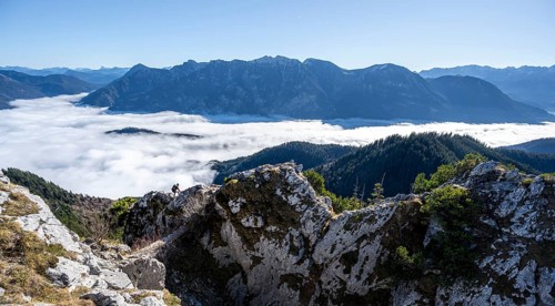 Hiker at Ettaler Manndl, view over mountain landscape and sea of clouds, high fog in the valley,