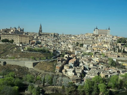 Historic old town with a river landscape and striking church towers, framed by hills, under a clear