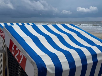 Close-up of blue and white beach chairs on the beach with the sea and a cloudy sky in the