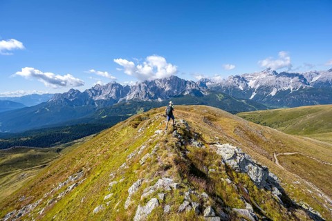 Mountaineers on a hiking trail between green mountain meadows on a mountain ridge, mountain