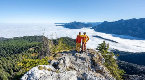 Two friends put their arms around each other's shoulders, mountaineers on the rocky summit of the