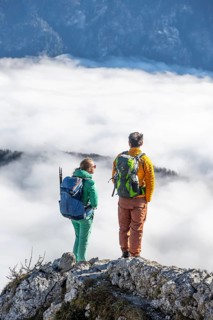 Two hikers at Ettaler Manndl, view over mountain landscape and sea of clouds, high fog in the