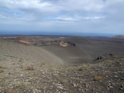 Vast desert landscape with views of the ocean and sky with clouds, barren landscape of lava