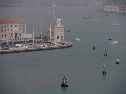 Venetian harbour with boats and yachts and a harbour wall surrounded by a foggy atmosphere, church